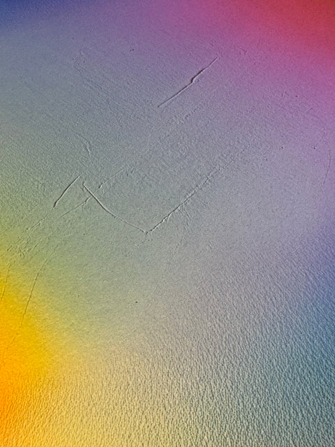 IMPACT 0018, close-up of the blank cream paper beside the disc, showing its fine texture under a soft blue, purple, pink, yellow, and green colour wash, with a couple of faint diagonal scratch lines.