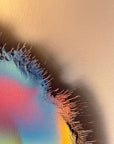 IMPACT 0016, close crop of the ragged edge where blue-black fringe threads fray against cream paper, with pink, red, and orange colour visible through the torn opening below the disc's rim.