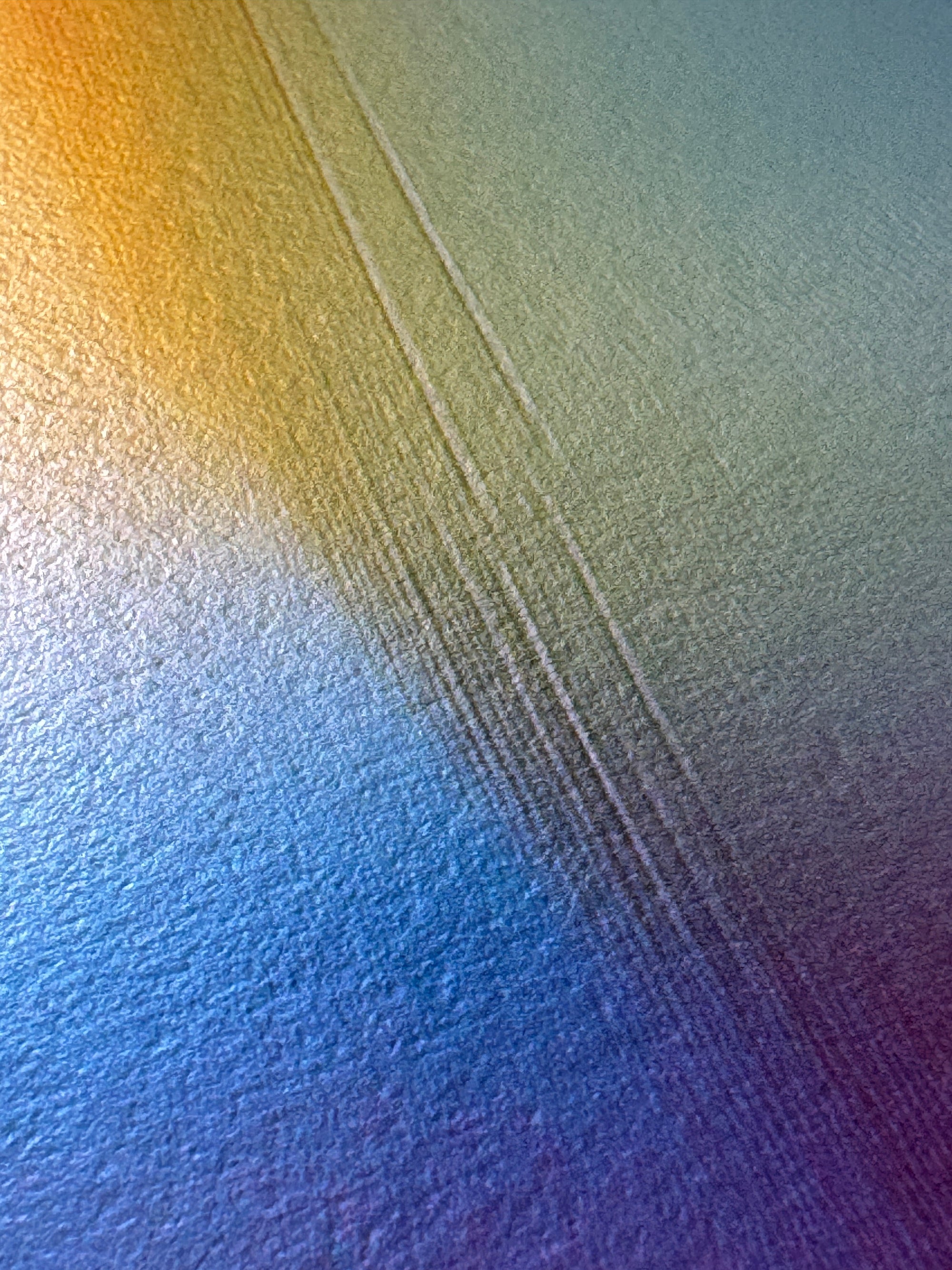 IMPACT 0016, close-up of the blank cream paper beside the disc, showing its fine woven texture and several faint parallel scratch lines under a soft yellow-to-blue-to-purple colour wash.