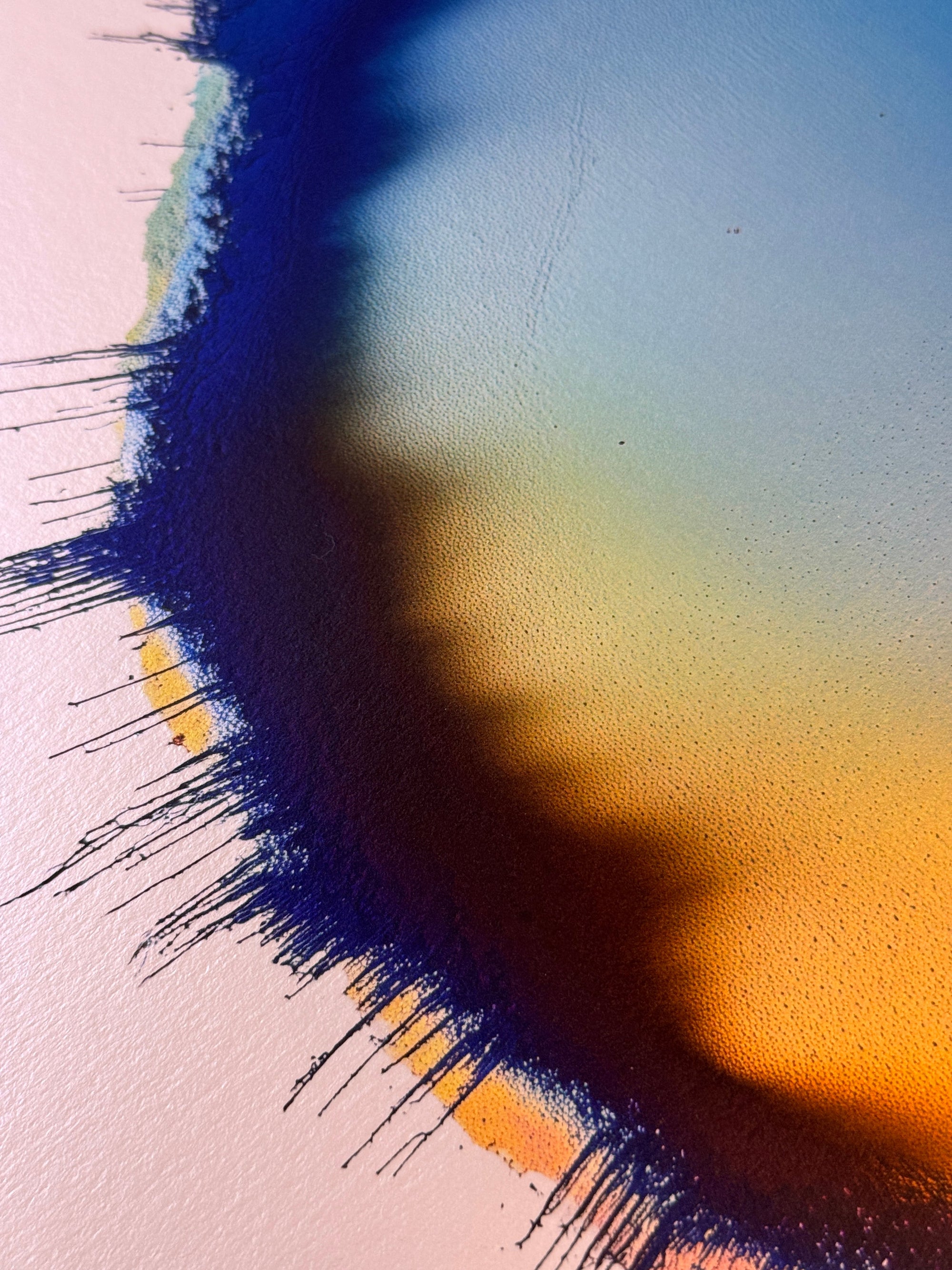 IMPACT 0017, close crop of the upper edge showing dark navy fringe at left, with a soft blue, green, and orange gradient on the paper crossed by a diagonal shadow from the disc's raised rim.