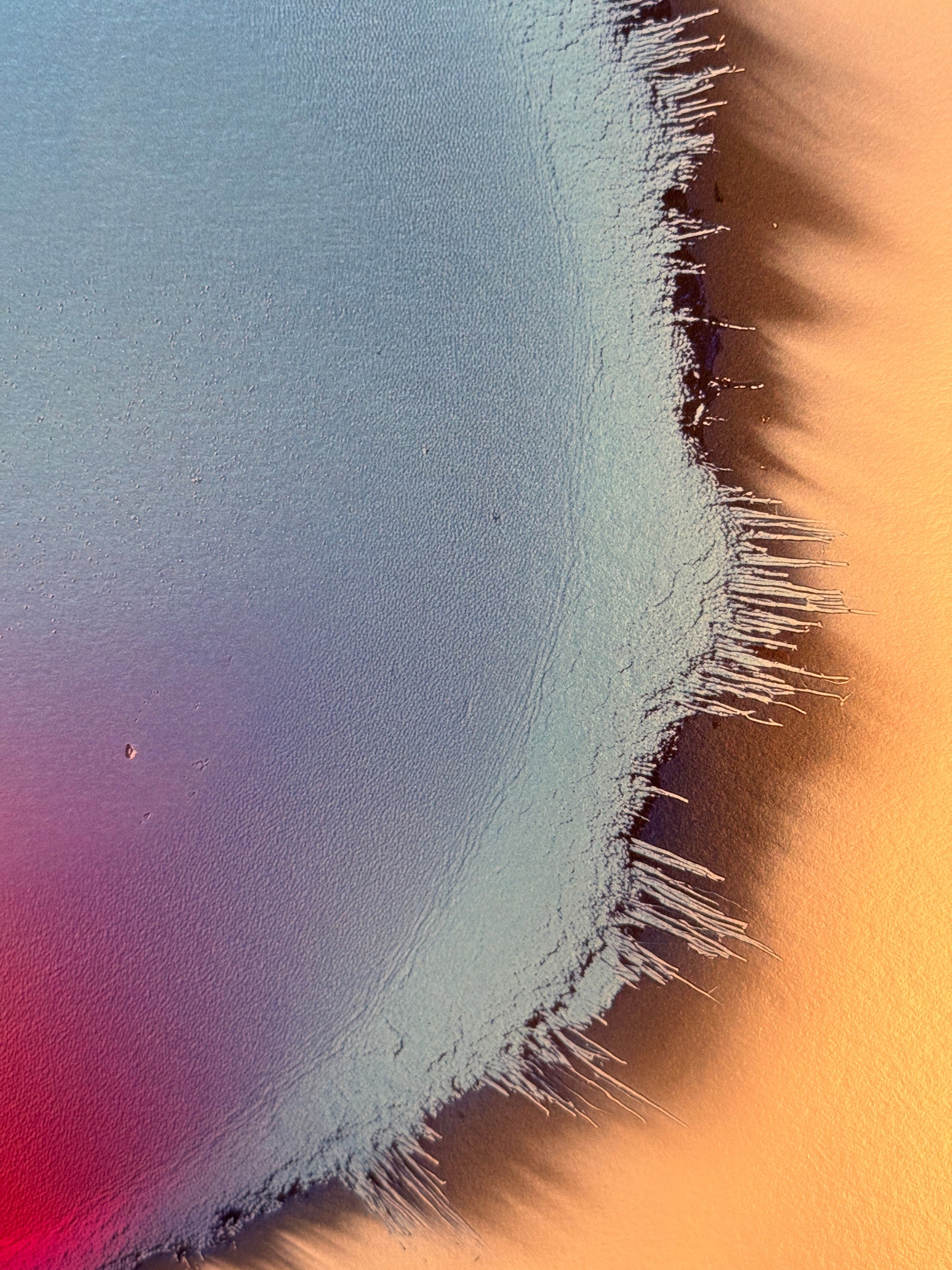 IMPACT 0017, close crop of the ragged edge where a pale blue-grey field frays into thin dark threads against warm orange paper, with small pinhole marks visible in the pale area.