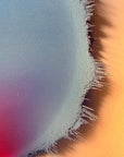 IMPACT 0017, close crop of the ragged edge where a pale blue-grey field frays into thin dark threads against warm orange paper, with small pinhole marks visible in the pale area.