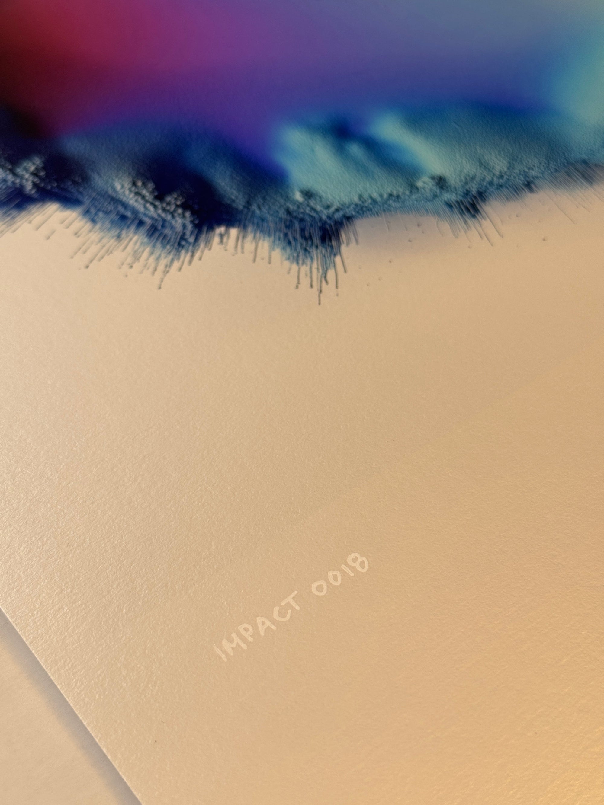 IMPACT 0018, close crop of the lower ragged edge showing magenta and blue above a dark navy fringe of fine dripping threads, with the pencil caption IMPACT 0018 written on the cream paper below.