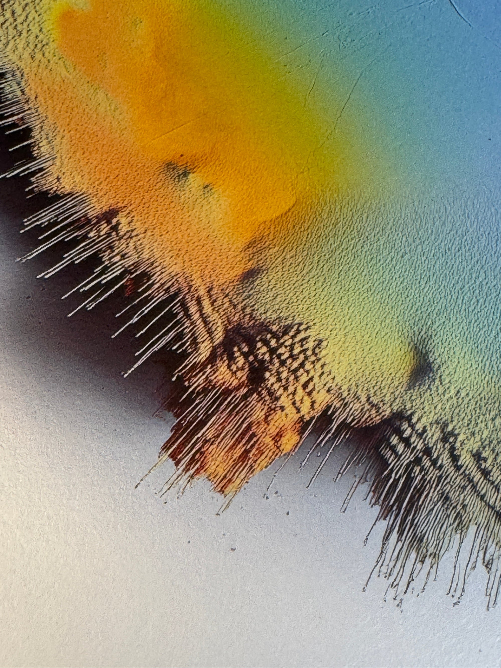 IMPACT 0018, close crop of the disc's edge where an orange-yellow area at upper left and a blue-green field at right are separated by a black-and-white checkered fringe of frayed pigment with drips.
