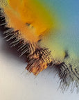 IMPACT 0018, close crop of the disc's edge where an orange-yellow area at upper left and a blue-green field at right are separated by a black-and-white checkered fringe of frayed pigment with drips.