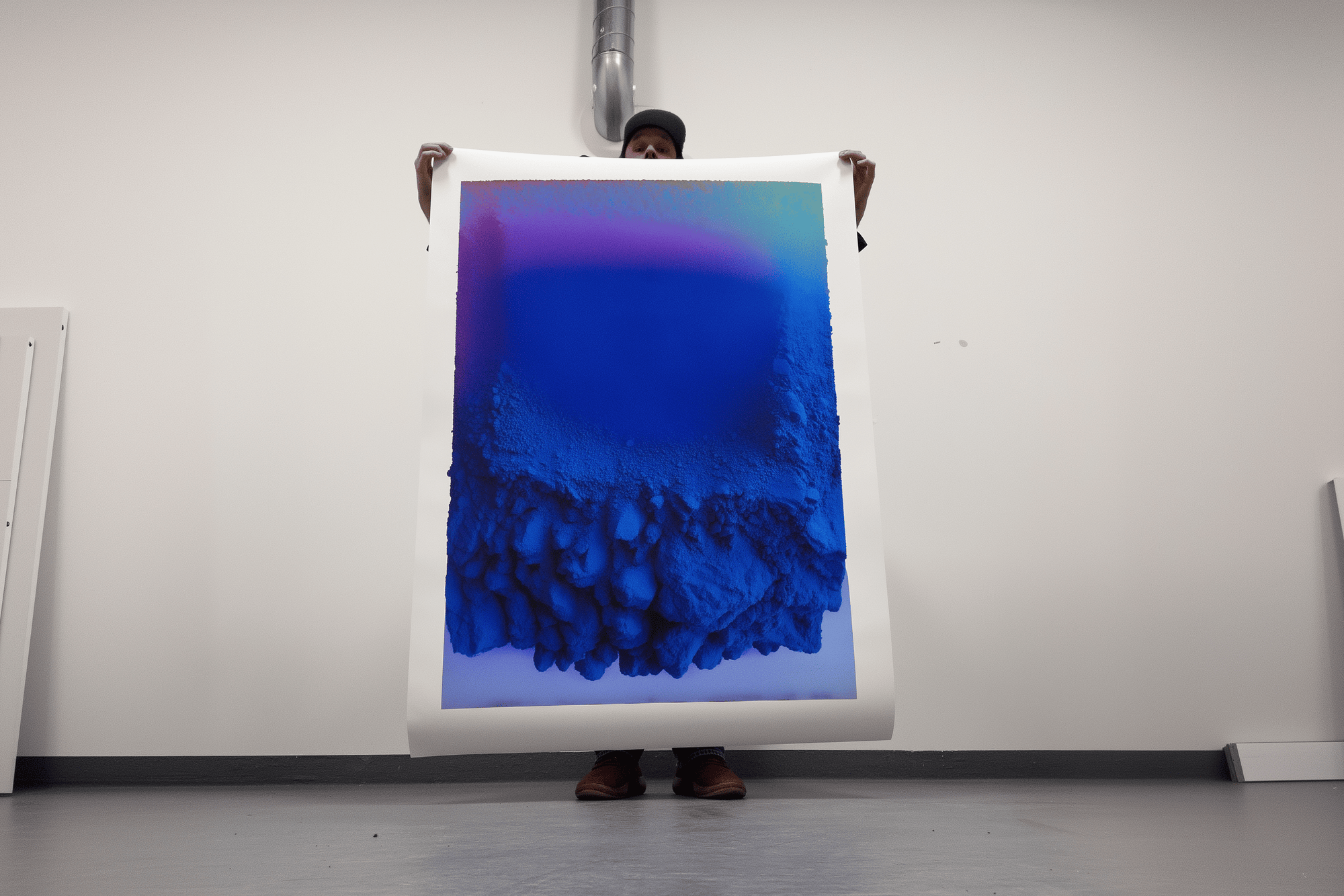 Person holding a large abstract painting with blue and purple hues.