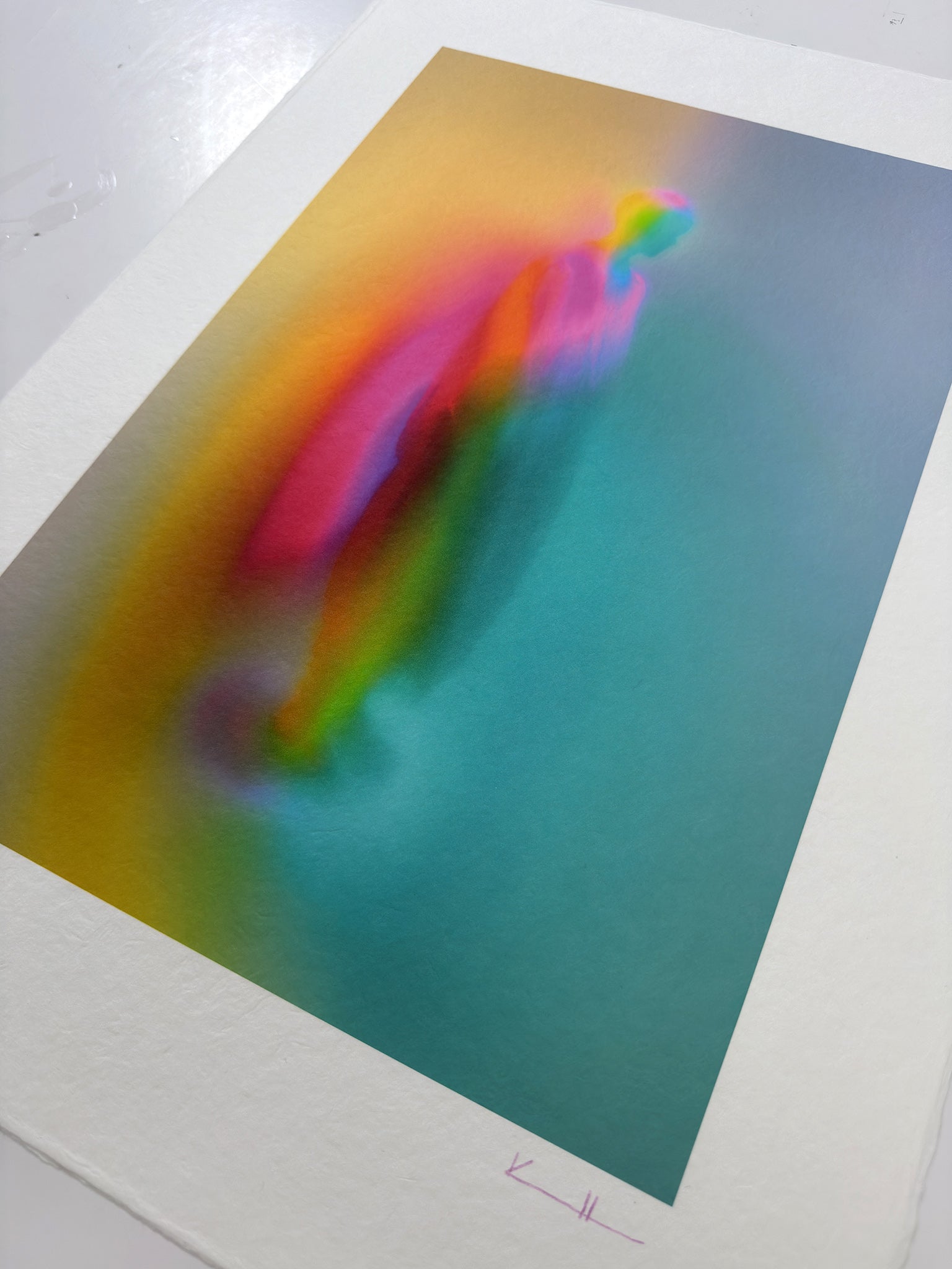 What Comes Back by Atelier Kalle Hellzén, hand-signed and numbered Limited Edition of 5, photographed at an angle on a light surface to show the weight and grain of the sheet. The figure sits in a teal-to-orange field; the signed "KH" mark is visible on the lower deckle edge. Giclée on handmade kozo washi.