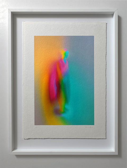 What Comes Back by Atelier Kalle Hellzén, hand-signed and numbered Limited Edition of 5, shown in a white frame on a pale wall. The print floats inside the mount, deckle edges visible, the figure rising through bands of orange, pink and teal. Giclée on handmade kozo washi.